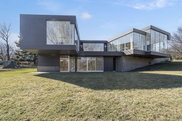 rear view of house featuring a sunroom and a lawn