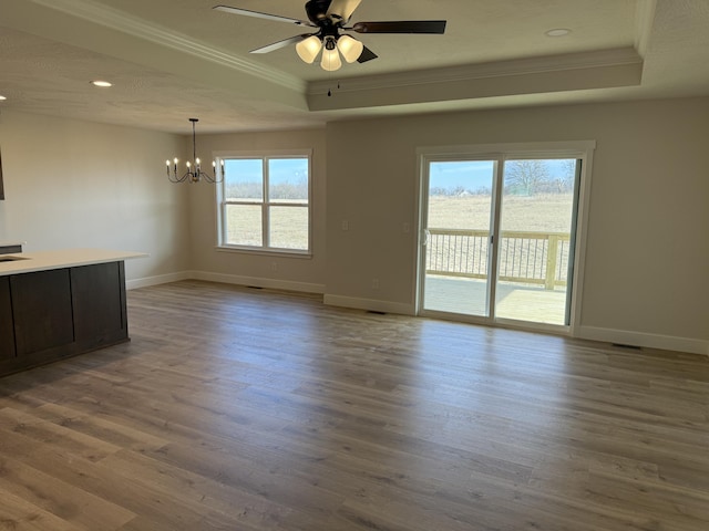 spare room featuring ornamental molding, light wood-type flooring, and a tray ceiling