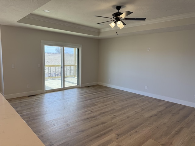 unfurnished room with crown molding, a tray ceiling, and hardwood / wood-style flooring