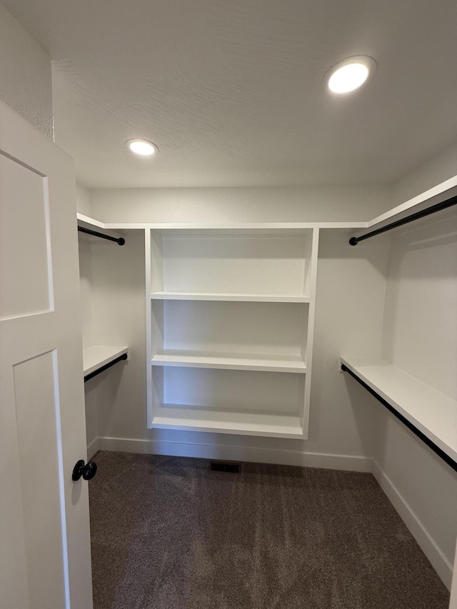 walk in closet featuring dark colored carpet