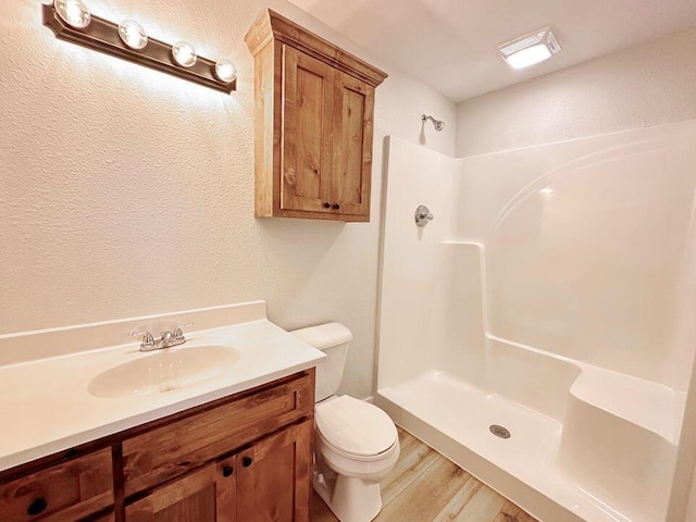 bathroom with walk in shower, vanity, toilet, and hardwood / wood-style floors