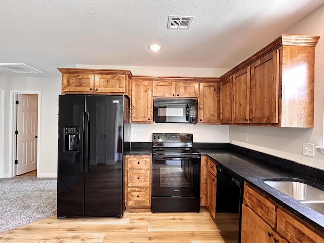 kitchen featuring sink, black appliances, a textured ceiling, and light wood-type flooring