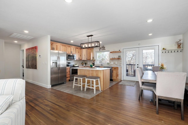 kitchen featuring appliances with stainless steel finishes, dark hardwood / wood-style flooring, hanging light fixtures, a center island, and french doors