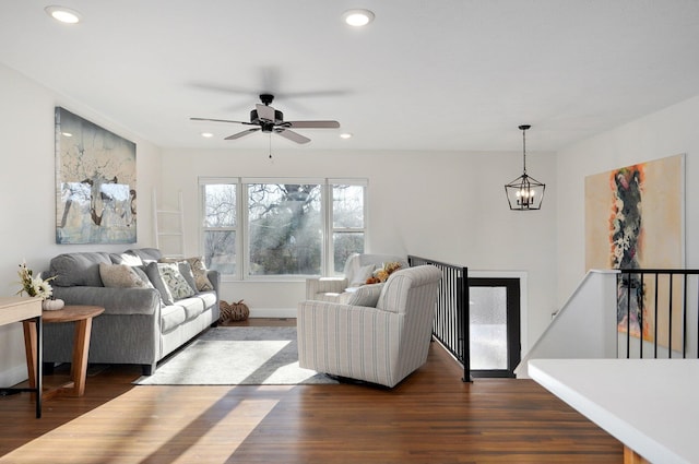 living room with dark hardwood / wood-style flooring and ceiling fan with notable chandelier