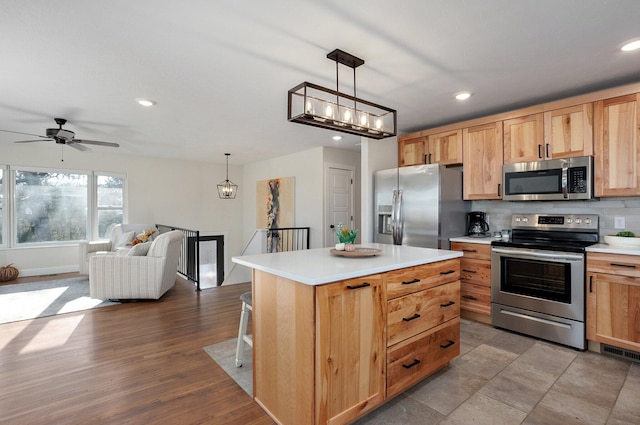 kitchen featuring pendant lighting, tasteful backsplash, stainless steel appliances, and a center island