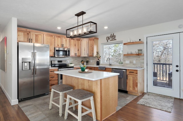 kitchen featuring a breakfast bar, tasteful backsplash, decorative light fixtures, a center island, and appliances with stainless steel finishes