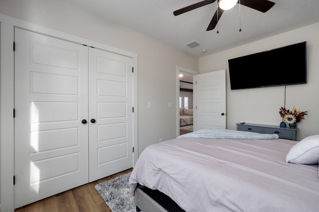 bedroom with dark wood-type flooring, ceiling fan, and a closet