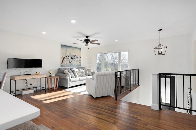 living room with ceiling fan with notable chandelier and dark hardwood / wood-style floors