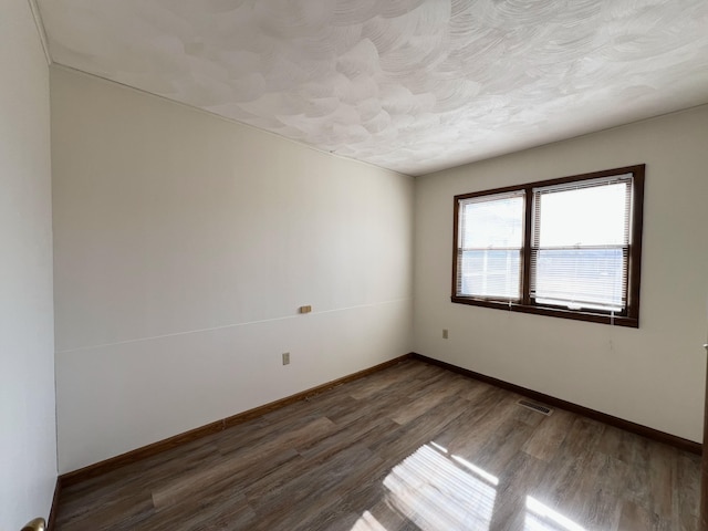 empty room featuring dark hardwood / wood-style floors and a textured ceiling