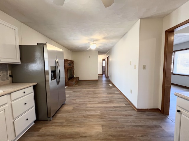 kitchen featuring white cabinetry, ceiling fan, a fireplace, and light hardwood / wood-style flooring