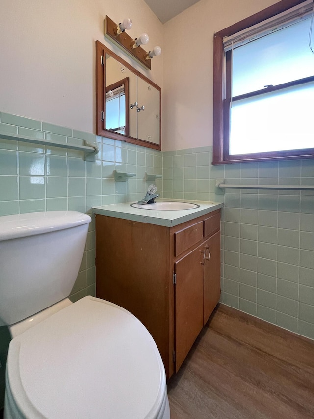 bathroom with tile walls, vanity, wood-type flooring, and toilet