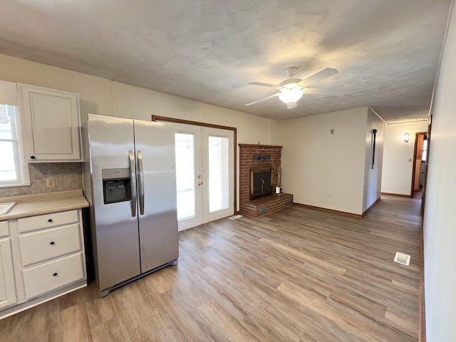 kitchen featuring tasteful backsplash, french doors, white cabinets, stainless steel fridge with ice dispenser, and light hardwood / wood-style flooring