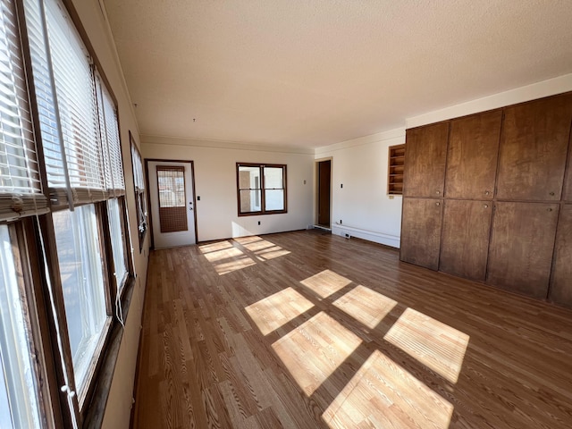 unfurnished living room featuring crown molding, dark wood-type flooring, and plenty of natural light