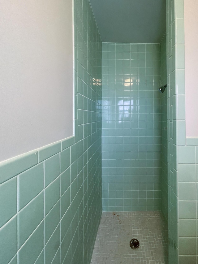 bathroom featuring a tile shower and tile walls