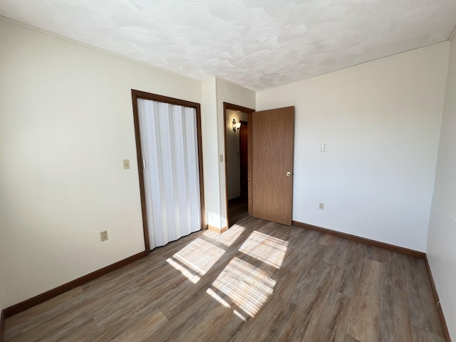 unfurnished bedroom with dark hardwood / wood-style flooring and a textured ceiling