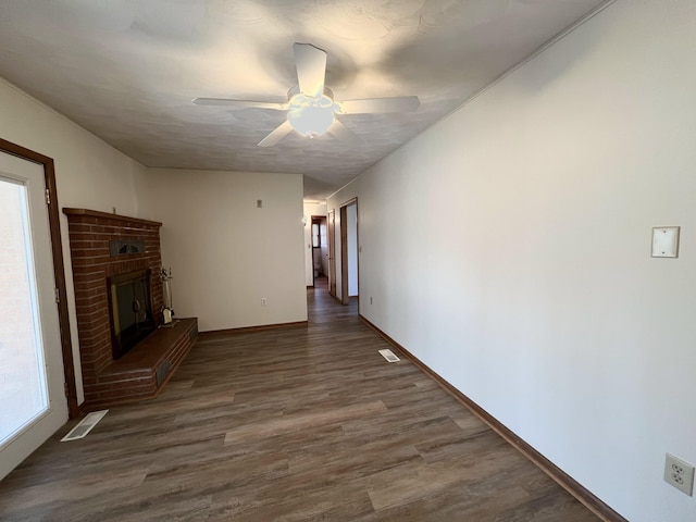 unfurnished living room featuring dark hardwood / wood-style flooring, a brick fireplace, and ceiling fan