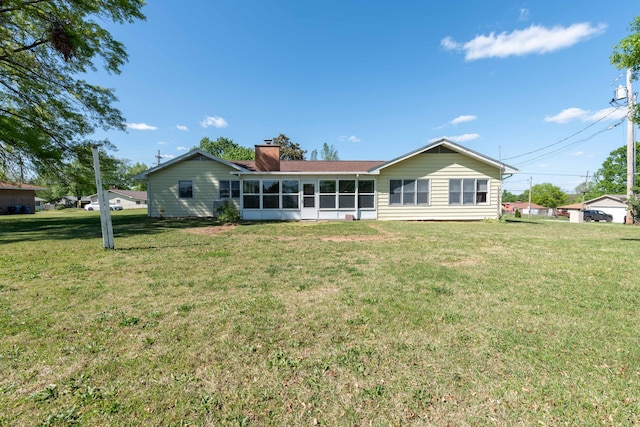 rear view of house with a sunroom and a lawn