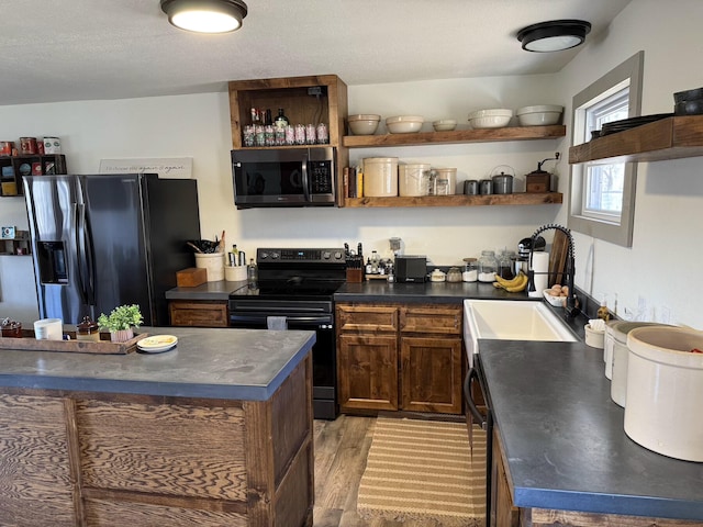 kitchen featuring light hardwood / wood-style floors, sink, a textured ceiling, and black appliances