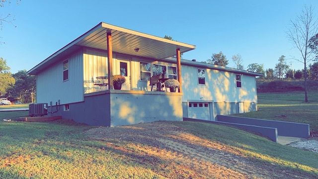 view of front of home with a porch, a garage, central AC unit, and a front lawn