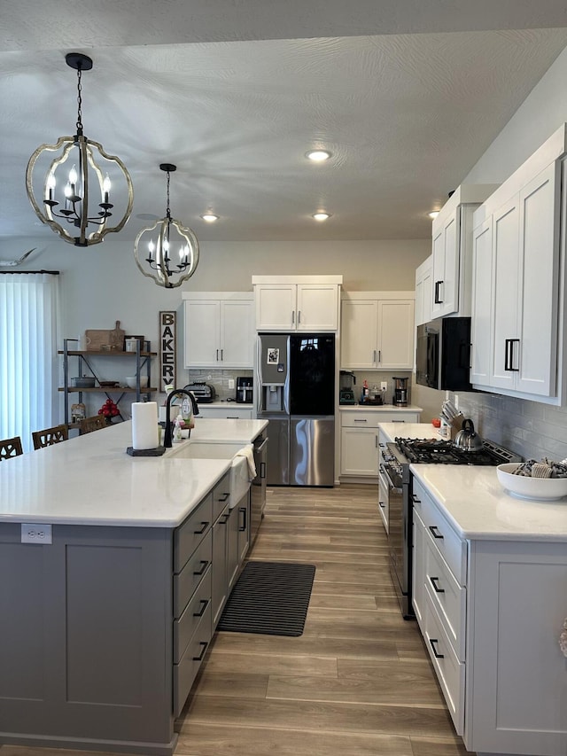 kitchen featuring white cabinetry, appliances with stainless steel finishes, tasteful backsplash, and pendant lighting