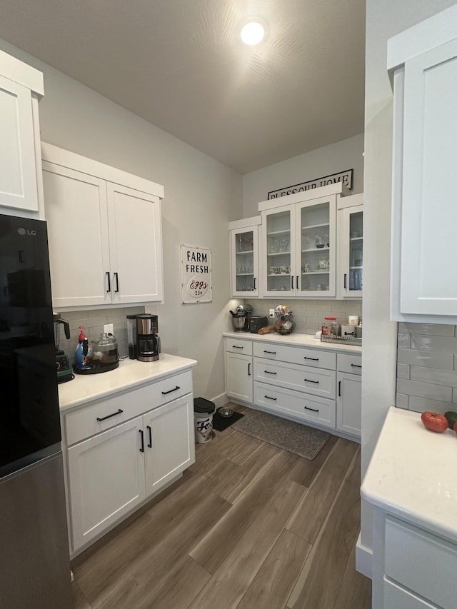 kitchen with tasteful backsplash, dark hardwood / wood-style flooring, fridge, and white cabinets