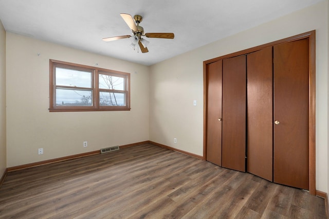 unfurnished bedroom featuring ceiling fan, dark hardwood / wood-style floors, and a closet