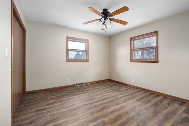 empty room with dark wood-type flooring and ceiling fan