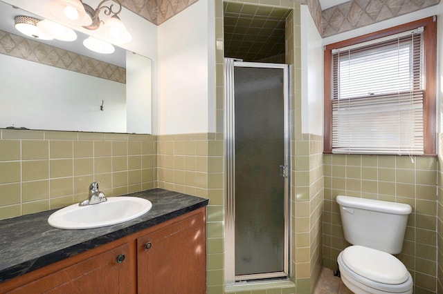 bathroom featuring an enclosed shower, vanity, toilet, and tile walls