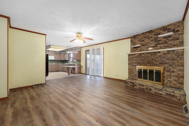 unfurnished living room featuring ornamental molding, dark wood-type flooring, ceiling fan, and a fireplace