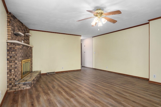 unfurnished living room with a brick fireplace, crown molding, dark wood-type flooring, and ceiling fan