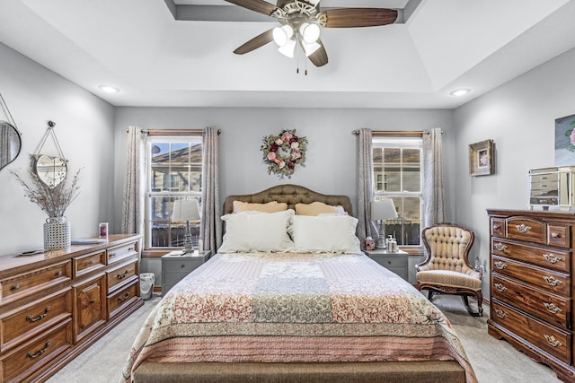 carpeted bedroom featuring ceiling fan and a raised ceiling