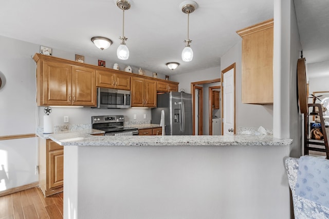 kitchen featuring pendant lighting, light hardwood / wood-style flooring, stainless steel appliances, light stone counters, and kitchen peninsula