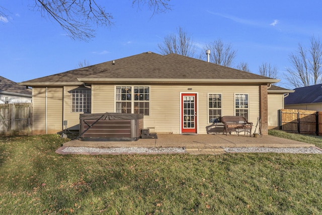 back of house featuring a hot tub, a patio, and a lawn