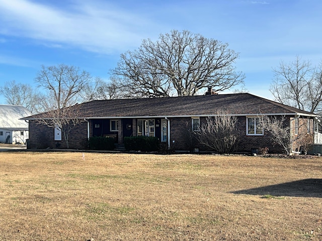 single story home featuring brick siding, a chimney, and a front lawn