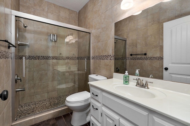 bathroom featuring tile walls, vanity, a shower with door, and toilet