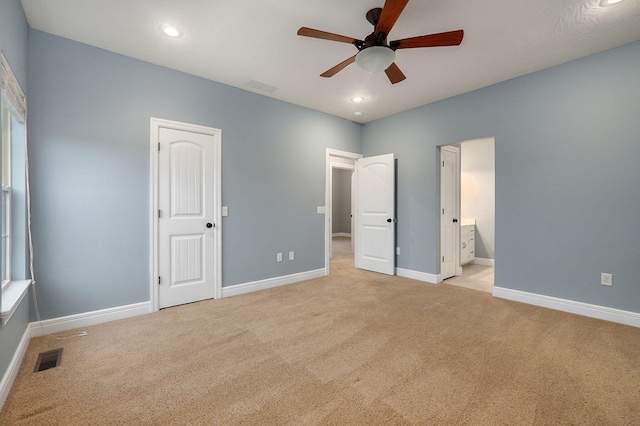 unfurnished bedroom with ensuite bath, light colored carpet, and ceiling fan