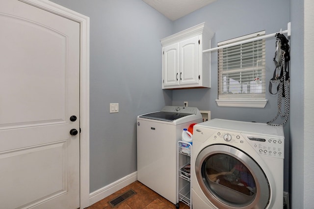 clothes washing area featuring independent washer and dryer, cabinets, and dark tile patterned flooring