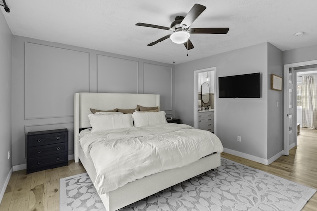 bedroom featuring ceiling fan, connected bathroom, a textured ceiling, and light wood-type flooring