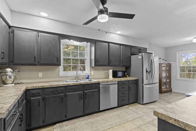 kitchen with appliances with stainless steel finishes, sink, backsplash, light tile patterned floors, and a textured ceiling