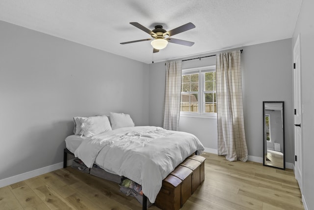 bedroom with ceiling fan, a textured ceiling, and light hardwood / wood-style flooring