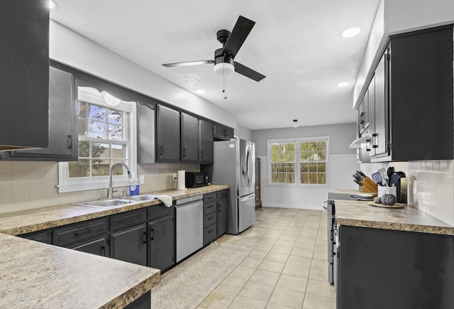 kitchen with light tile patterned flooring, appliances with stainless steel finishes, sink, and backsplash