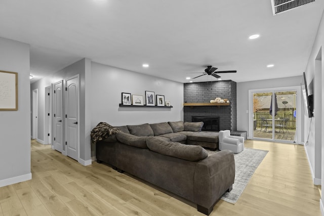 living room featuring light hardwood / wood-style flooring, a fireplace, and ceiling fan