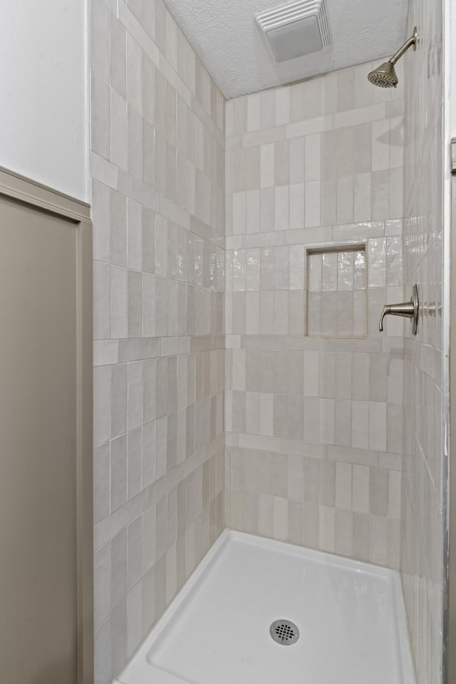 bathroom featuring tiled shower and a textured ceiling