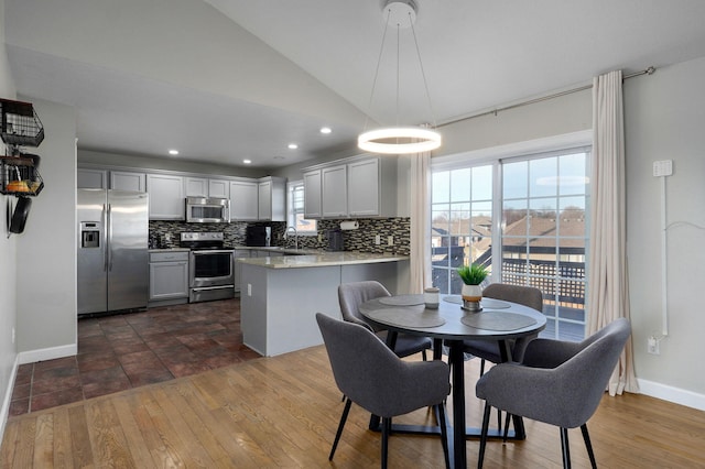 kitchen with stainless steel appliances, tasteful backsplash, decorative light fixtures, and kitchen peninsula