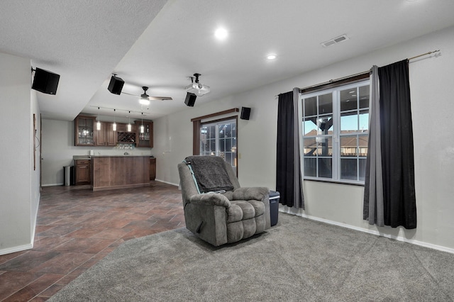 living area with ceiling fan, bar area, and a textured ceiling