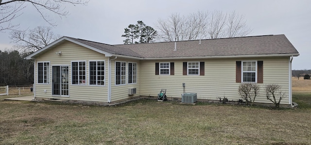 rear view of house with central AC and a lawn