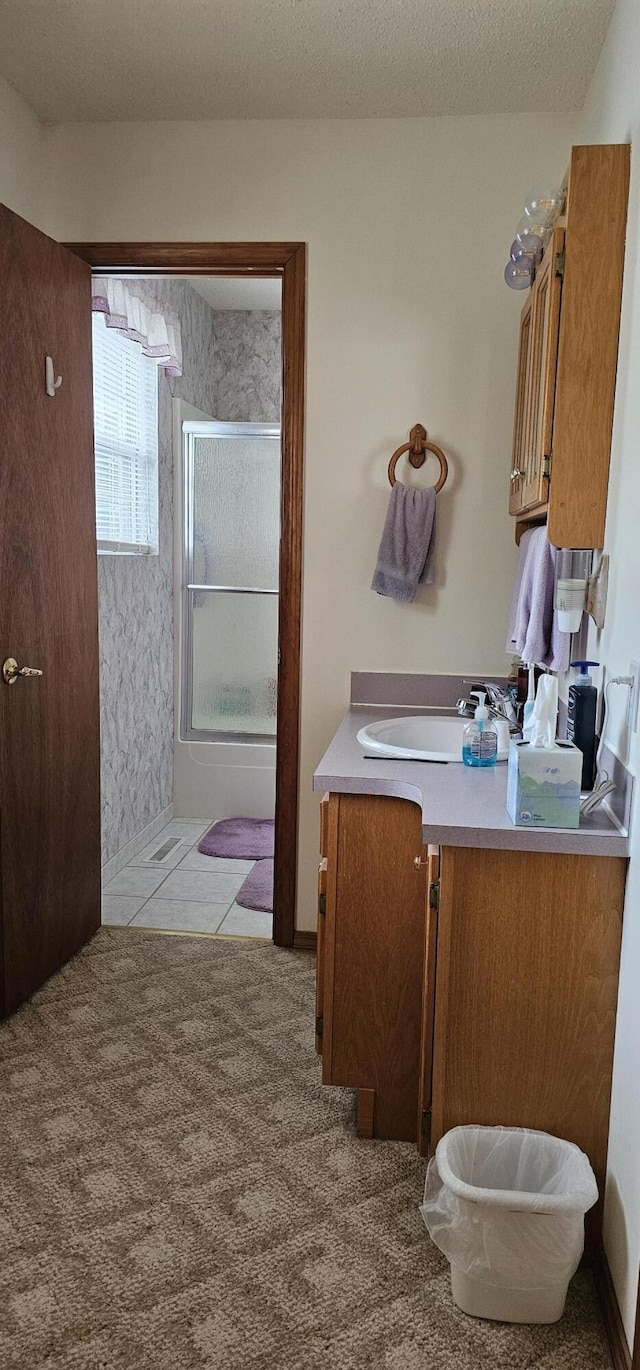 bathroom featuring vanity, a shower with shower door, tile patterned floors, and a textured ceiling