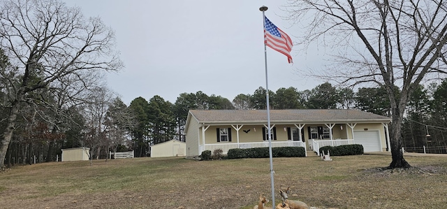 view of front of home featuring a porch, a storage unit, a front yard, and a garage