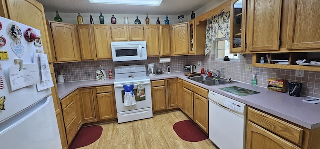 kitchen with sink, white appliances, light hardwood / wood-style flooring, backsplash, and a textured ceiling