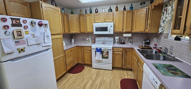 kitchen featuring sink, white appliances, light hardwood / wood-style floors, and backsplash